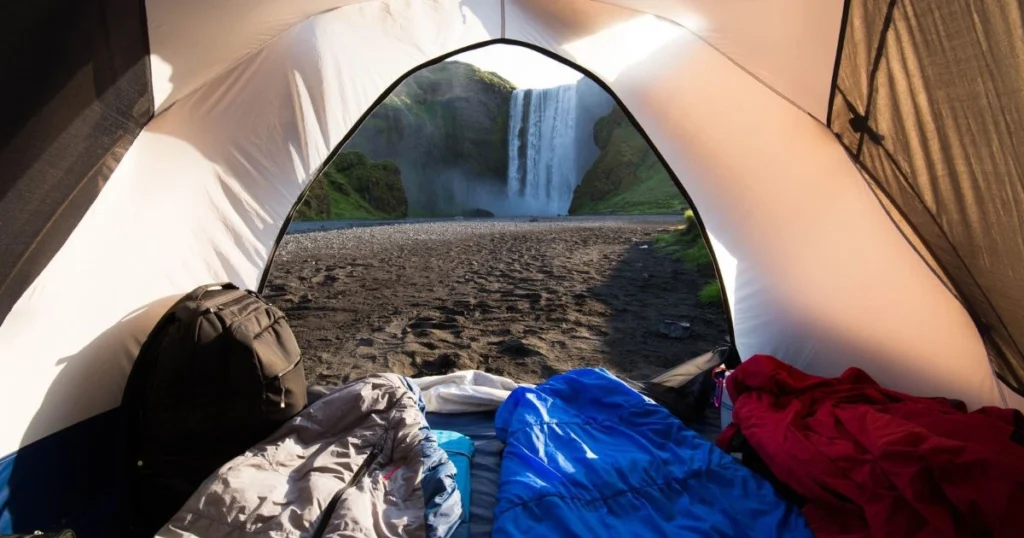 Camping inside a tent with sleeping bags and a backpack, illustrating shelter and sleeping gear.